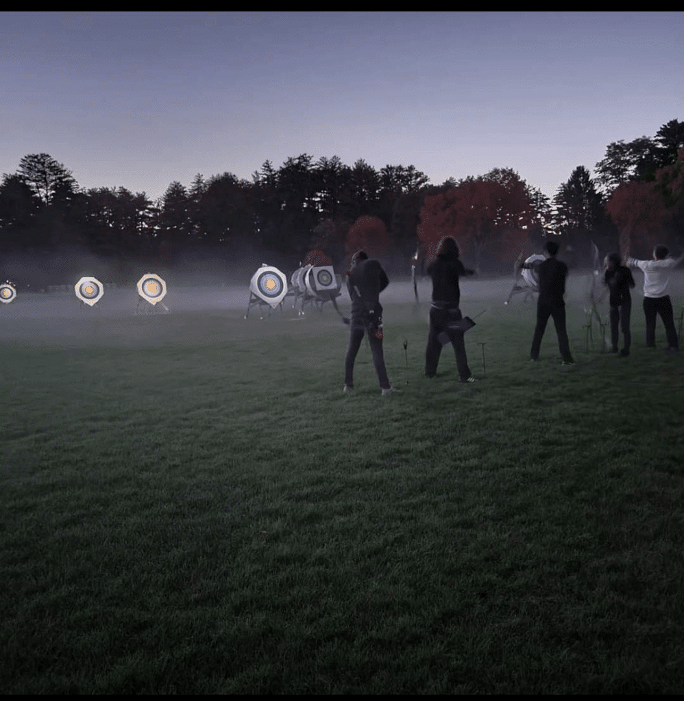Archers shooting at targets in a field at dusk